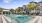 a pool in a courtyard with palm trees and buildings in the background